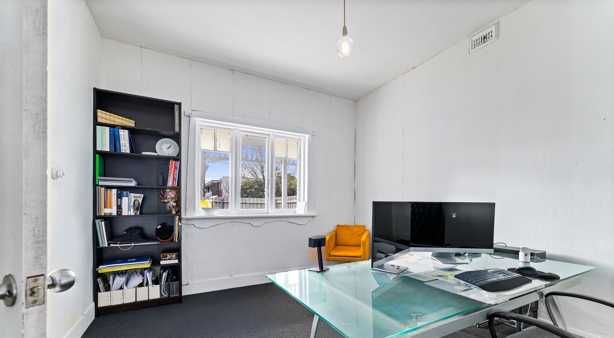 209 Ballarat Road office interior - glass desk, dual monitors, bookshelf and dark carpet