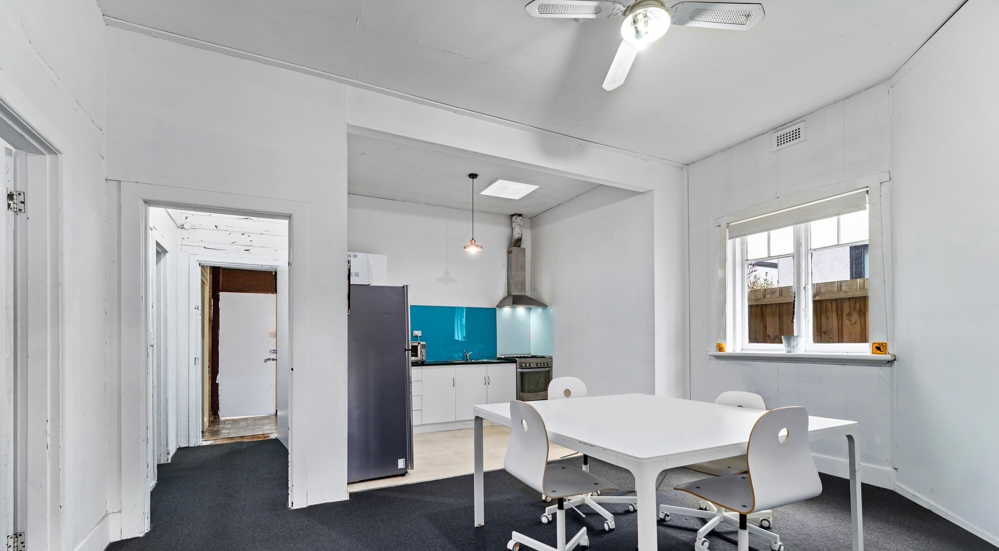 209 Ballarat Road meeting room - white table, office chairs and teal kitchen beyond