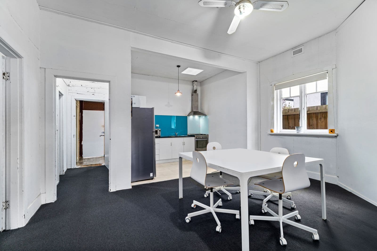 Ballarat Road meeting room - white table, office chairs and teal kitchen beyond