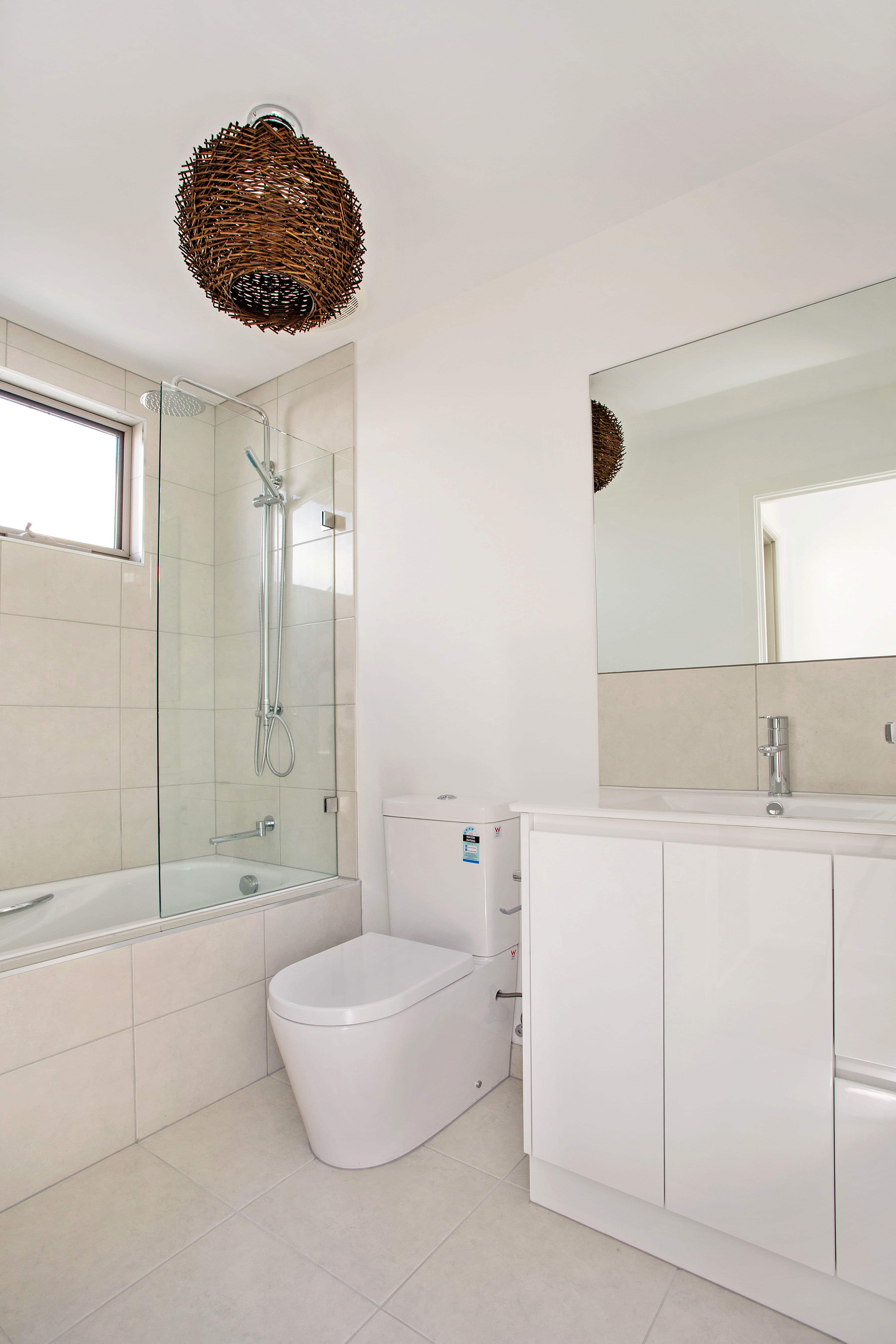 Chatham Street bathroom - bath and shower combo with neutral tiles and pendant light