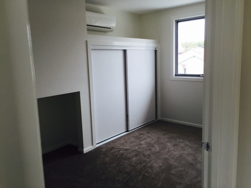 Finished Foreman Way room - dark charcoal carpet laid, sliding wardrobe closed, split system AC and natural light from window