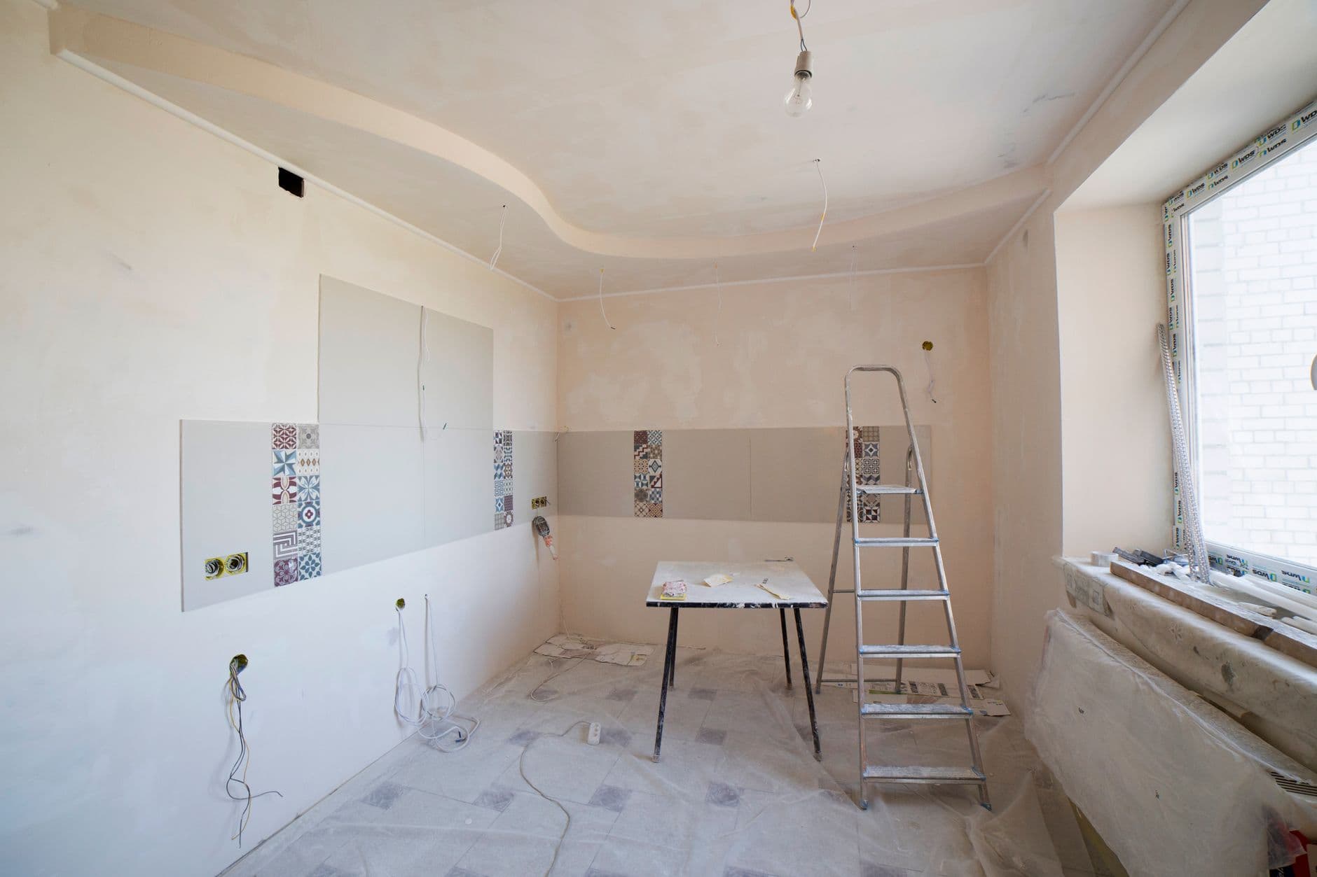 Apartment room mid-renovation with plastering and tiling underway
