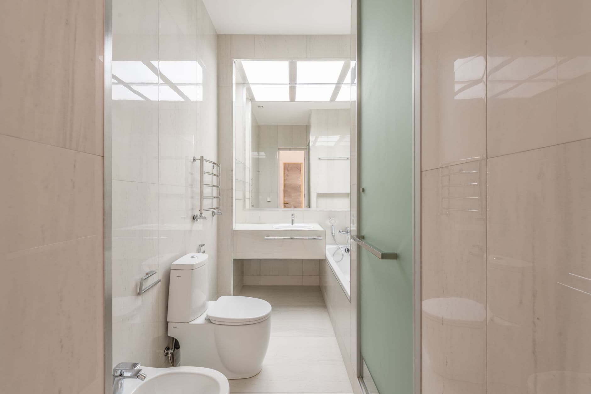 Narrow ensuite bathroom with heated towel rail and frosted glass shower screen