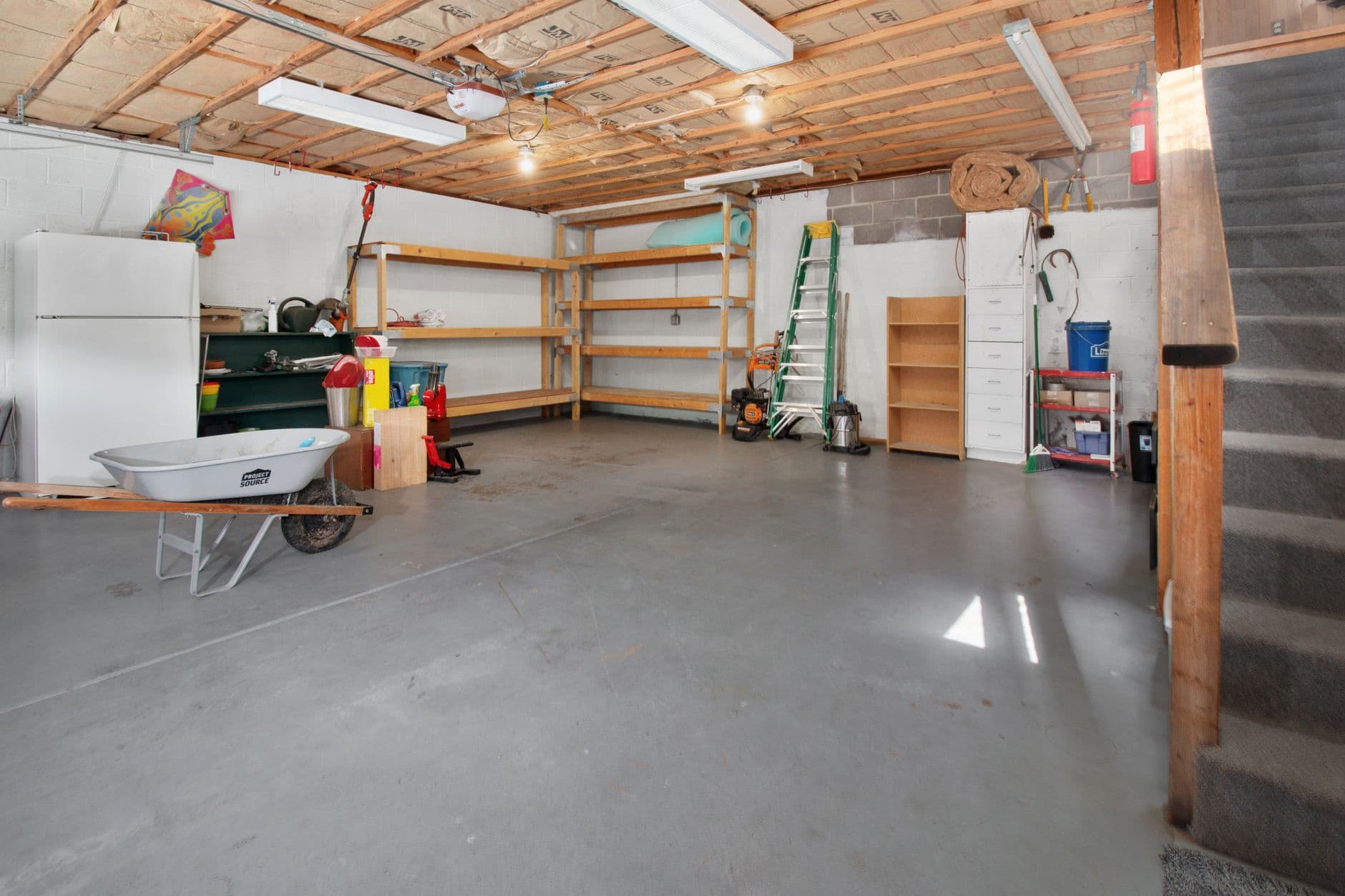 Empty single garage with bare concrete slab and exposed roof framing before conversion