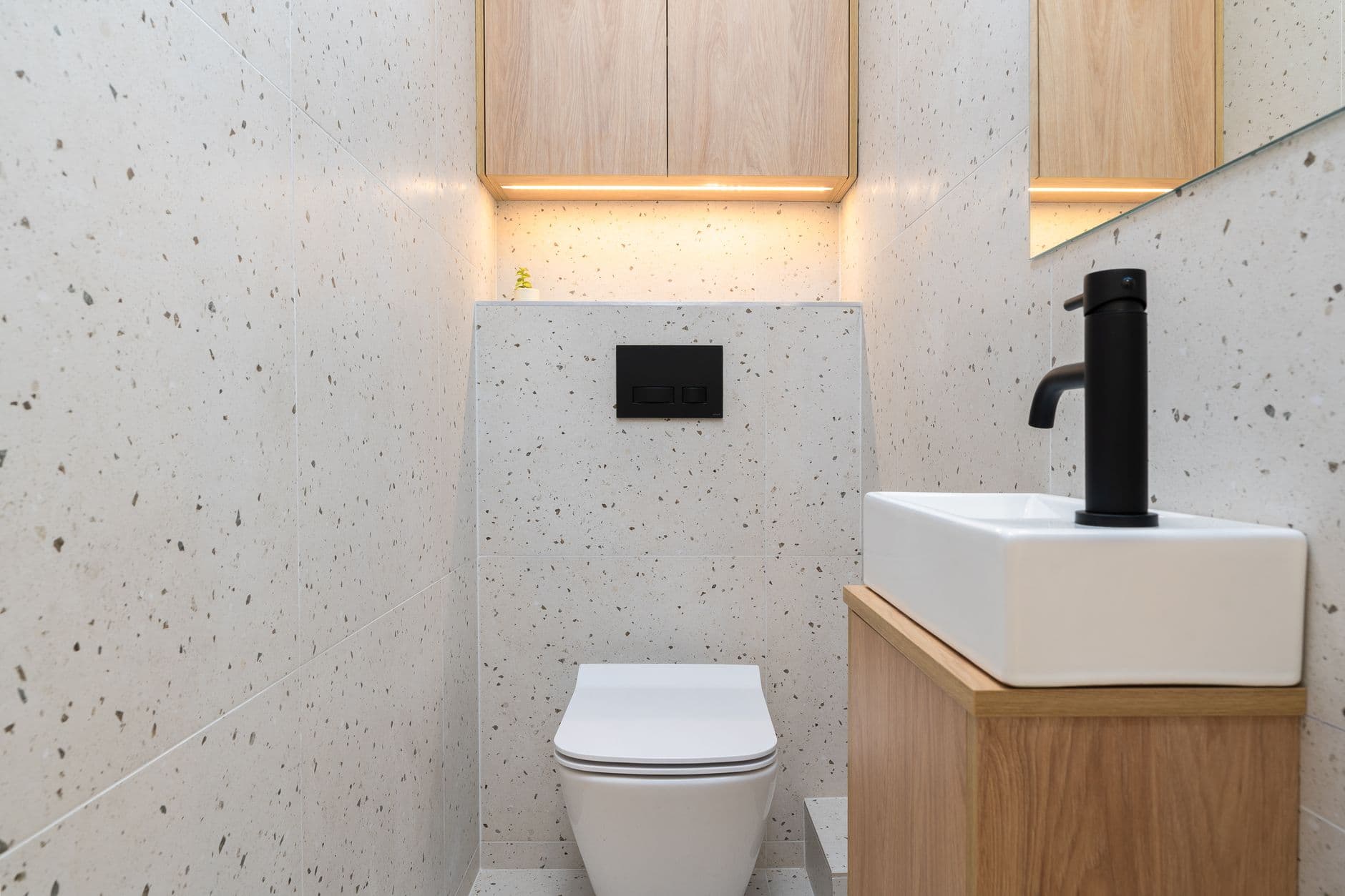 Compact bathroom with wall-hung vanity, large mirror and light terrazzo-style tile