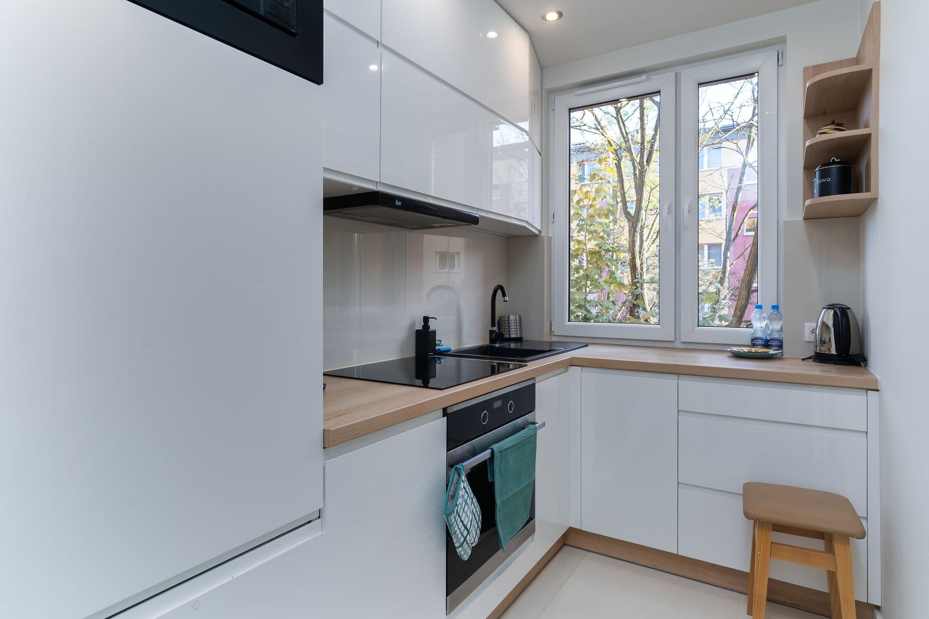 Compact L-shaped kitchen with light timber benchtop and white cabinetry