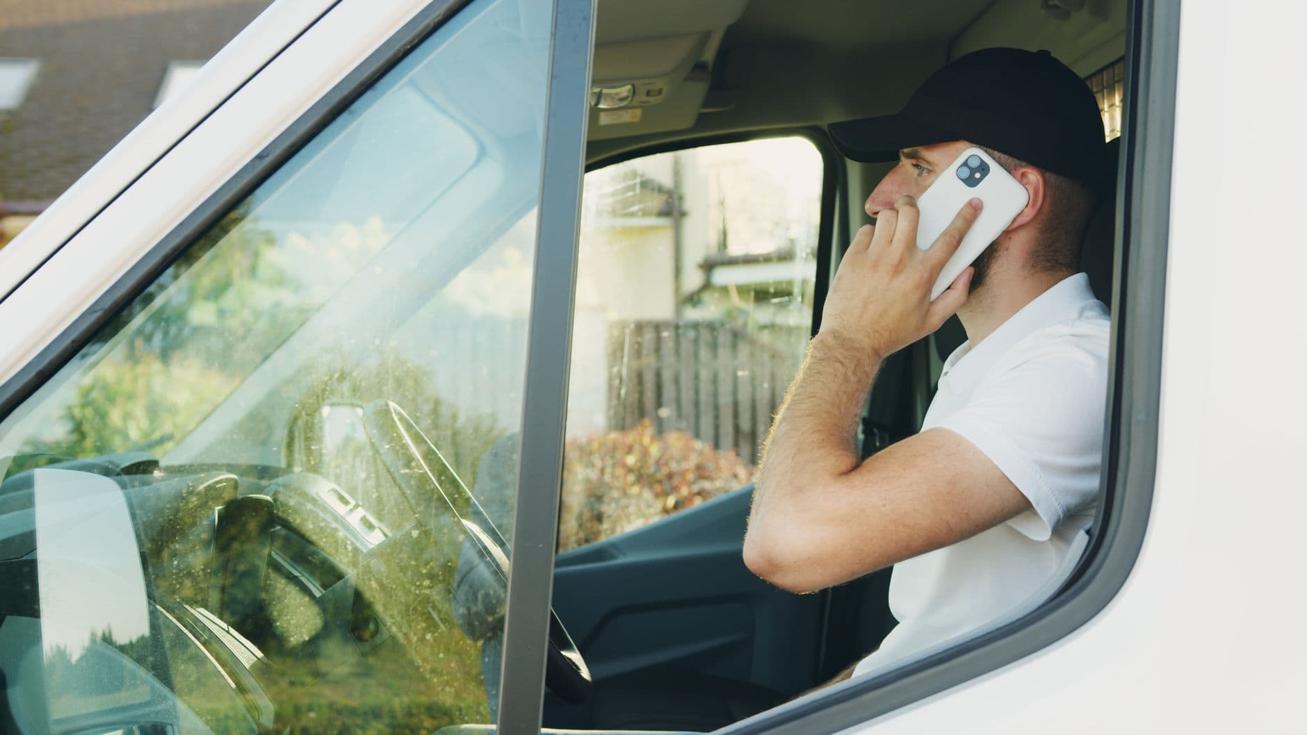 Tradesperson taking a phone call from the driver's seat of a work van