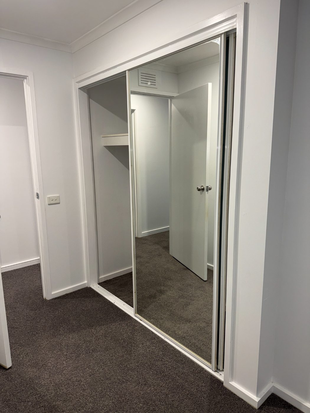 Master bedroom after renovation - charcoal carpet and fresh repaint